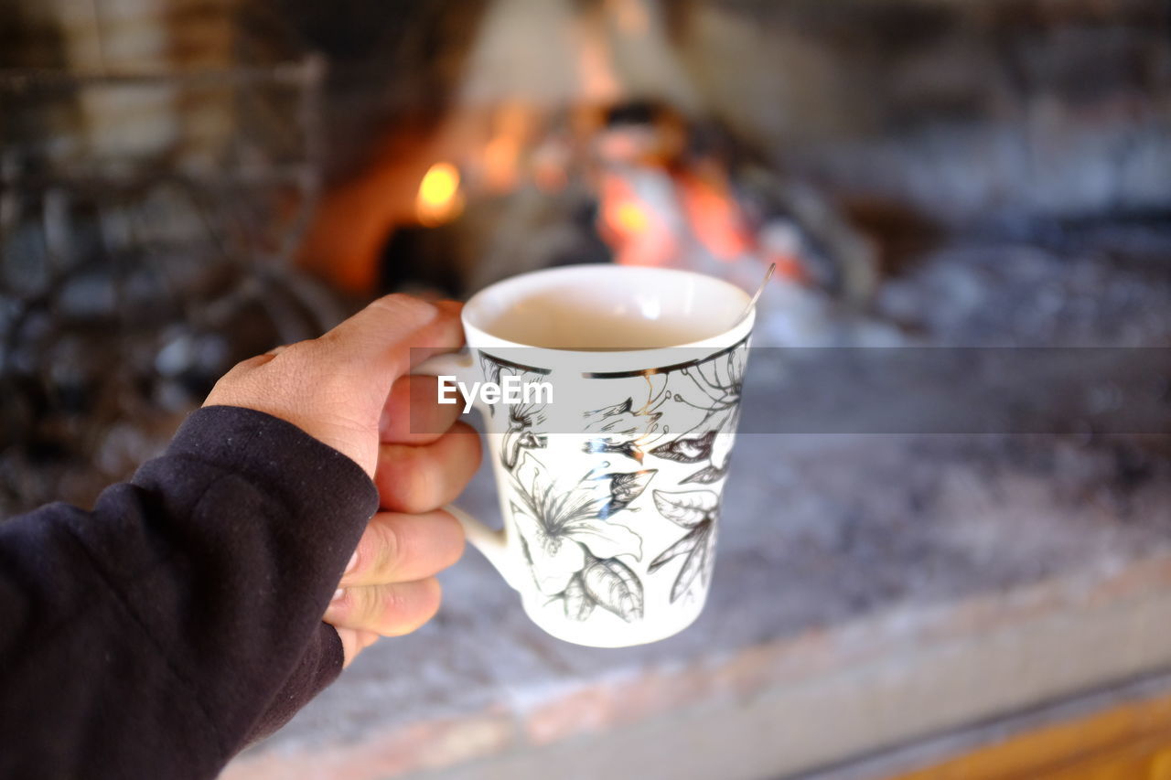 CLOSE-UP OF HAND HOLDING TEA LIGHT CANDLE