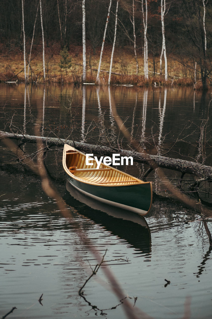 A beautiful green canadian canoe floating on the forest lake. tranquil and calm autumn scene 