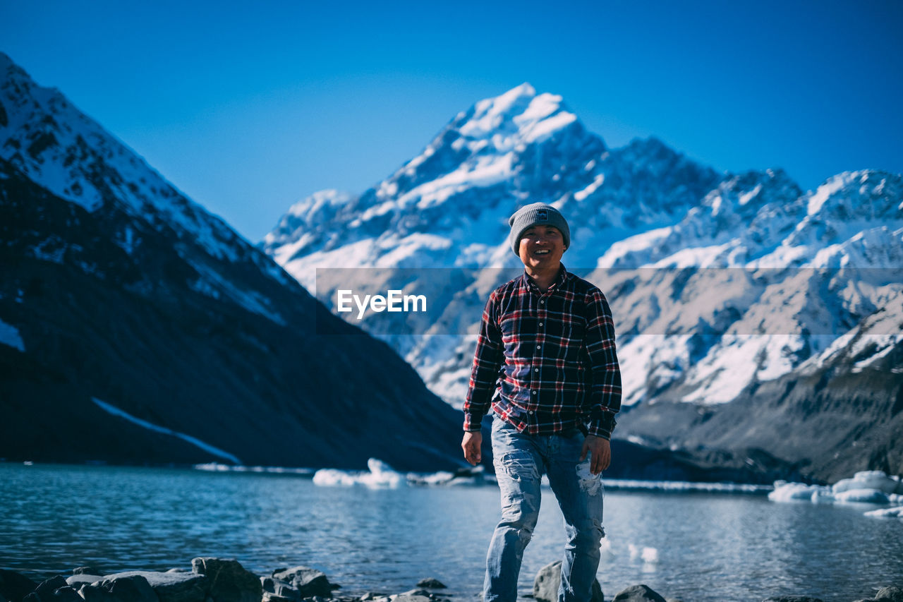 Portrait of man standing on snowcapped mountain against sky