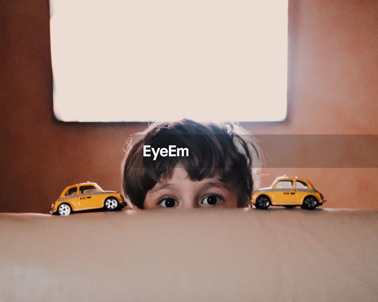 Cropped portrait of boy with toy cars on sofa