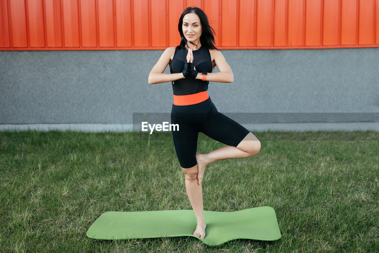 Beautiful middle-aged girl in sports clothes does yoga outdoors. 