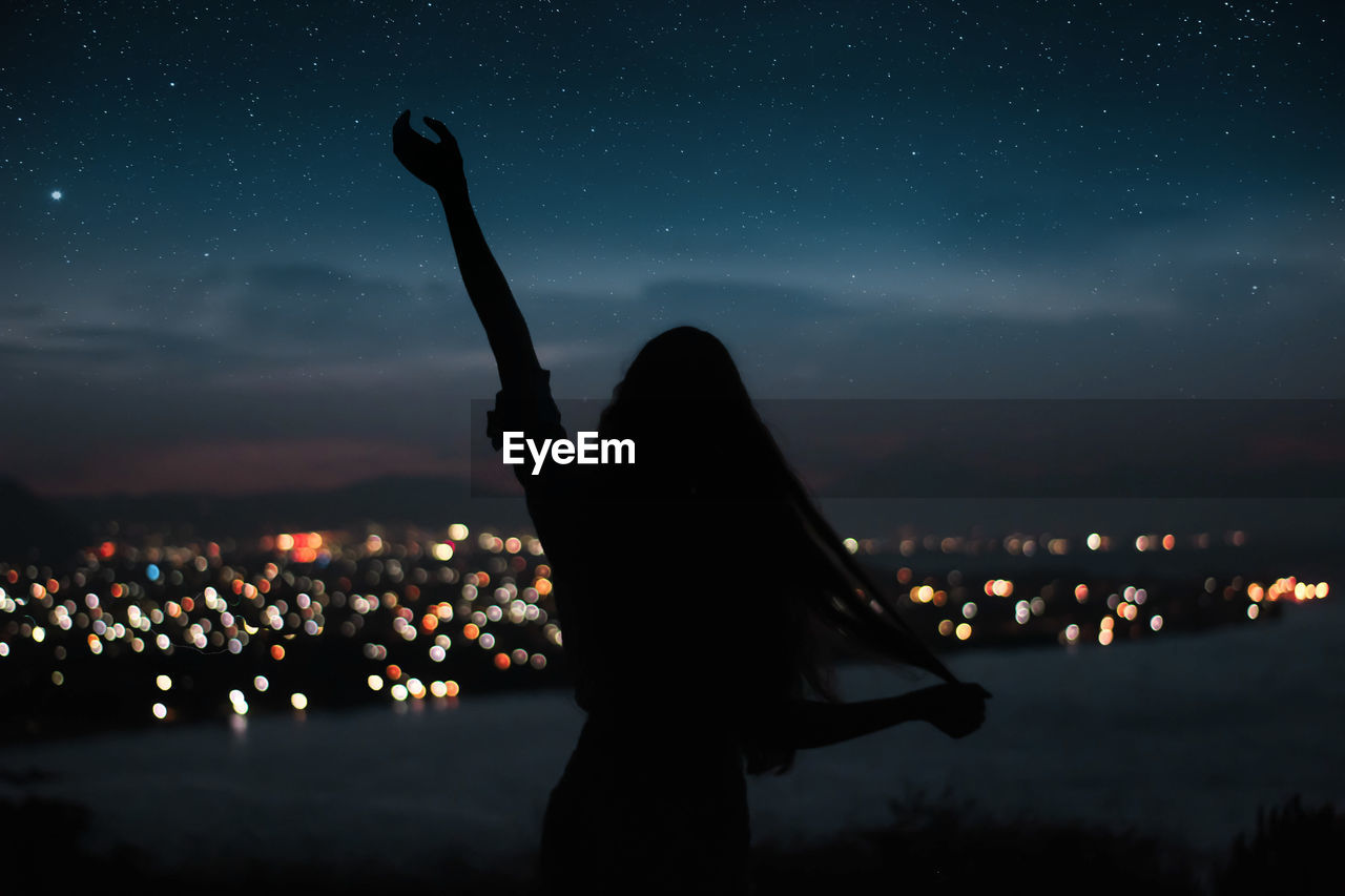 Silhouette woman standing against sky at night