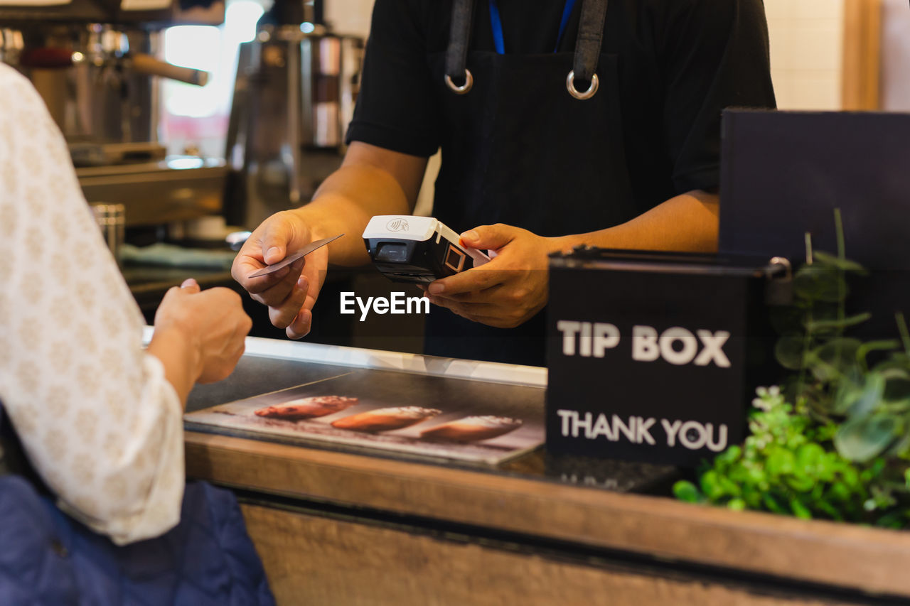 Asia woman use cashless wifi paywave scan on card reader in coffee shop