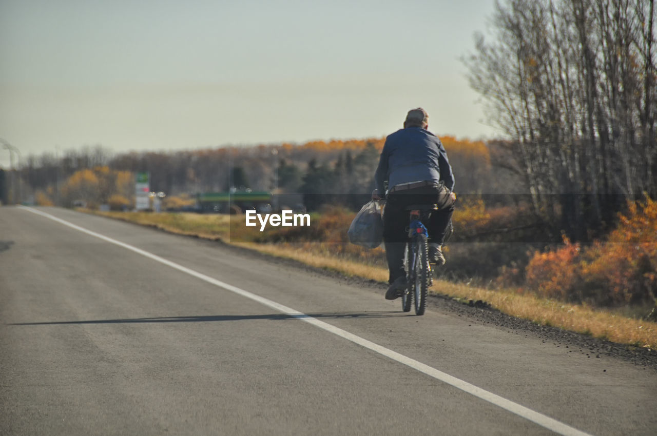 Rear view of man riding bicycle on road