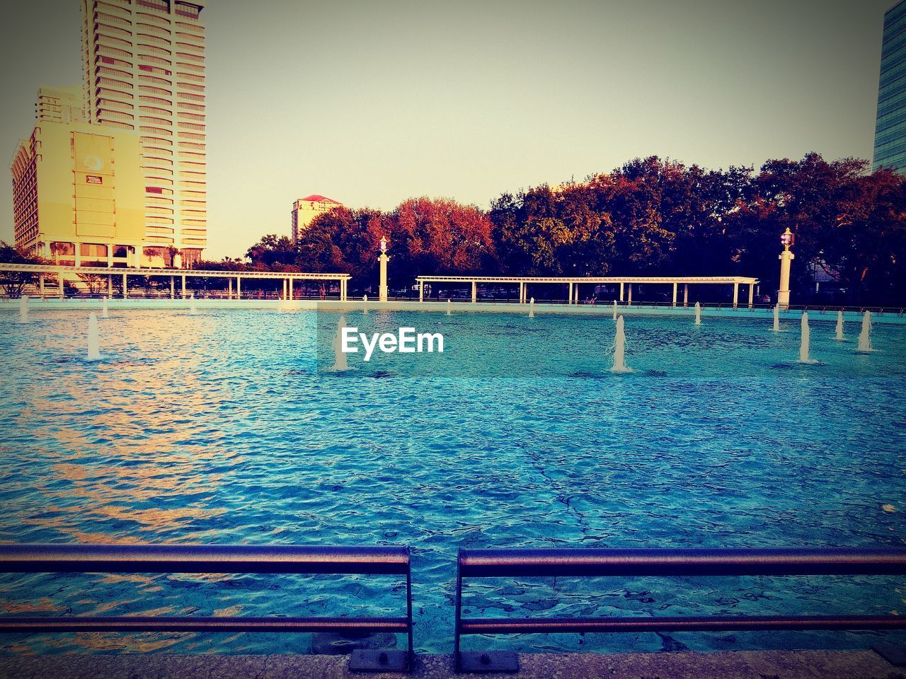 SCENIC VIEW OF SWIMMING POOL BY RIVER AGAINST BUILDINGS