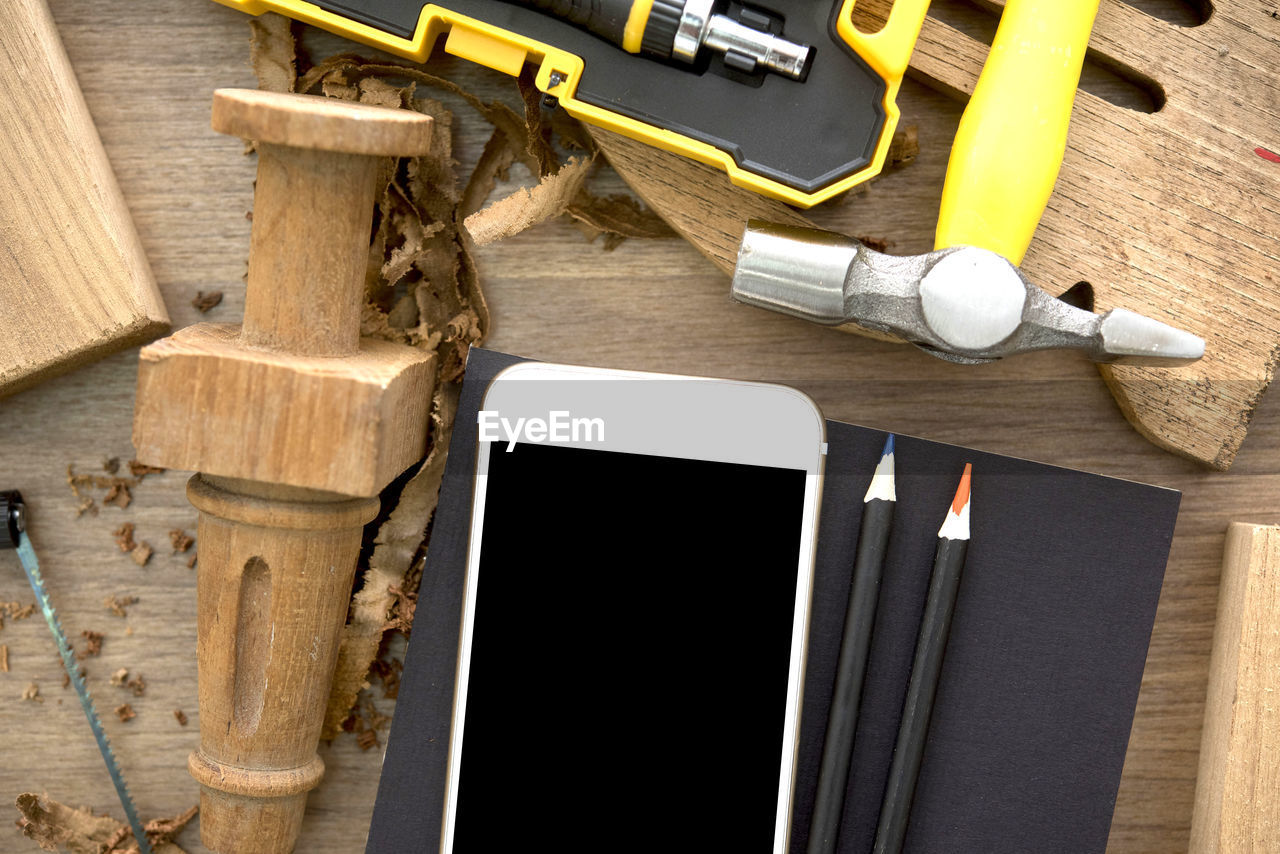 Directly above shot of mobile phone with wood and hand tools on table