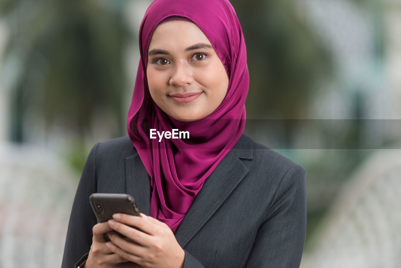 PORTRAIT OF A SERIOUS YOUNG WOMAN USING SMART PHONE