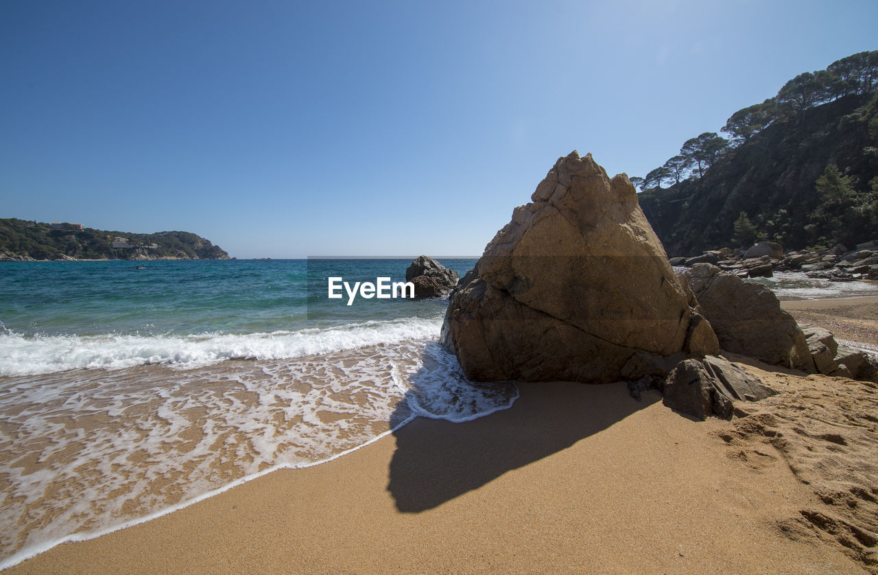 View of rocks on beach against clear sky