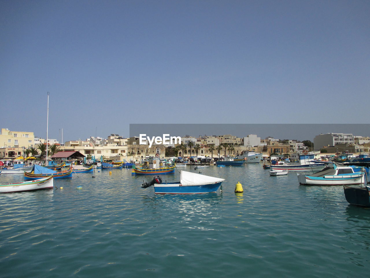 Boats moored in harbor against clear sky