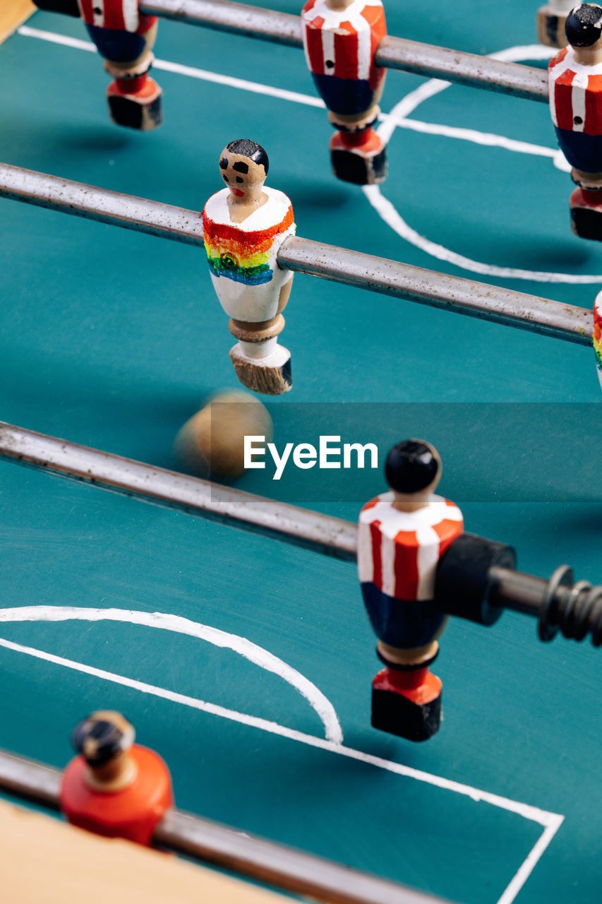 High angle of detail of retro table soccer with wooden miniature figurines of players on metal bars