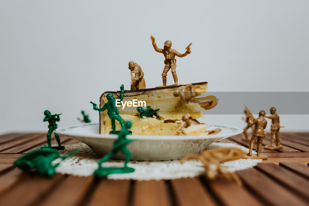 Army of toy soldiers fighting on the top of a piece of cake - close up white background