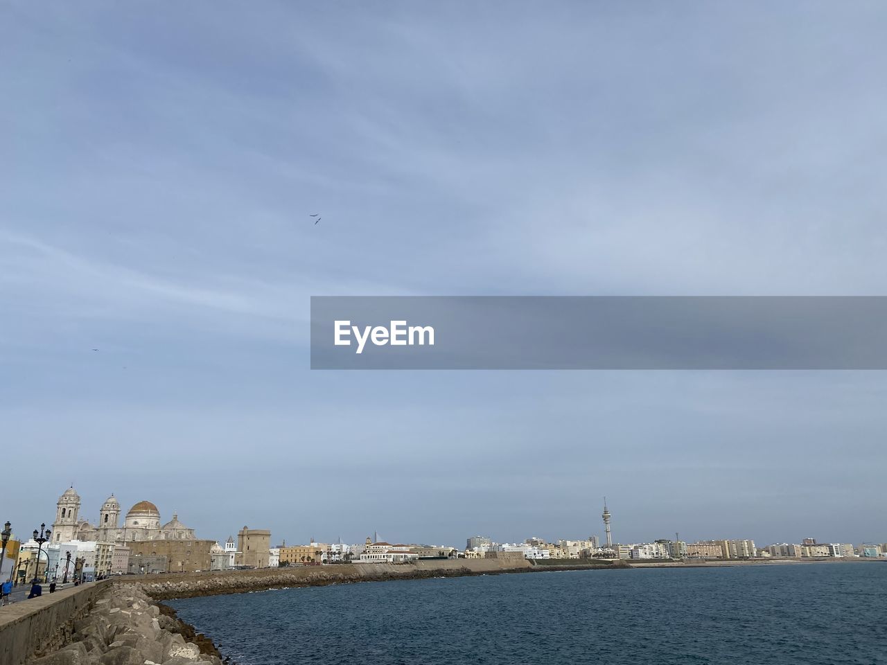 Sea by buildings against sky in city