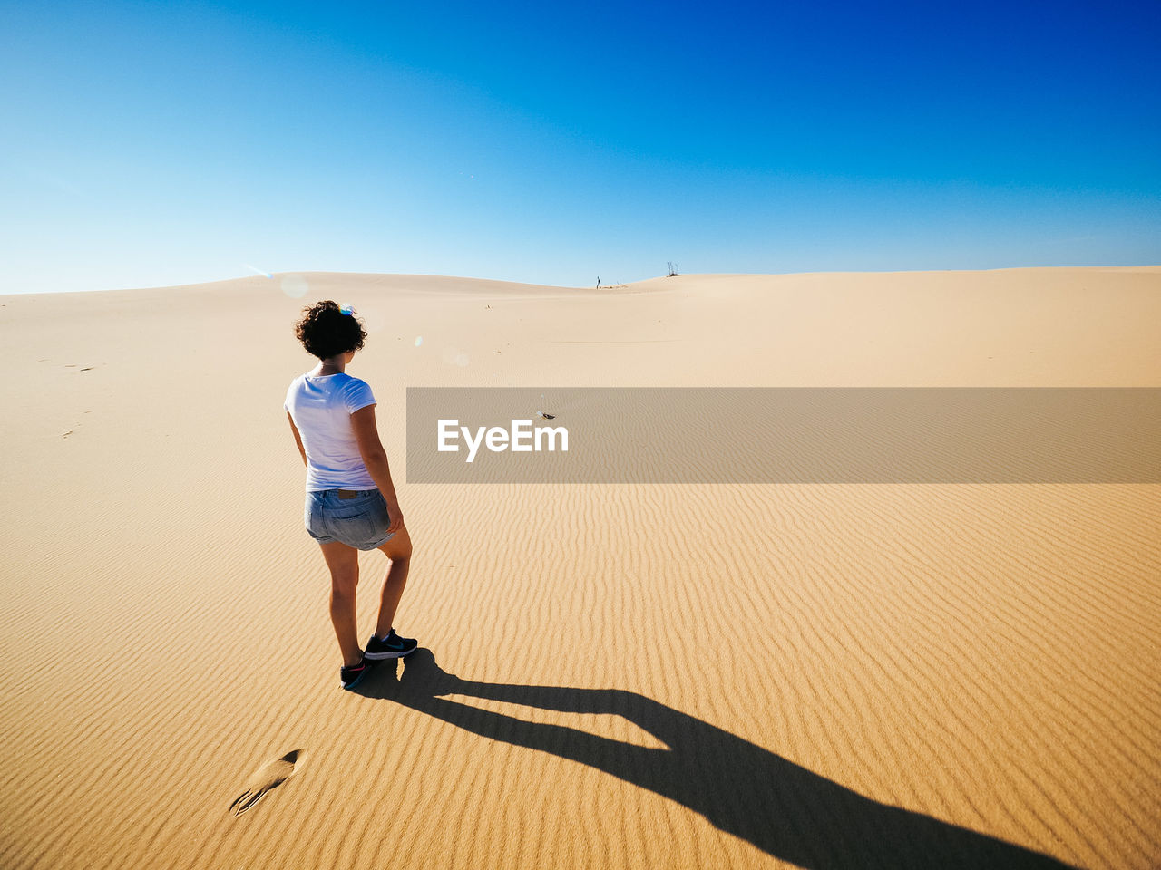 Rear view of woman standing on sand dune