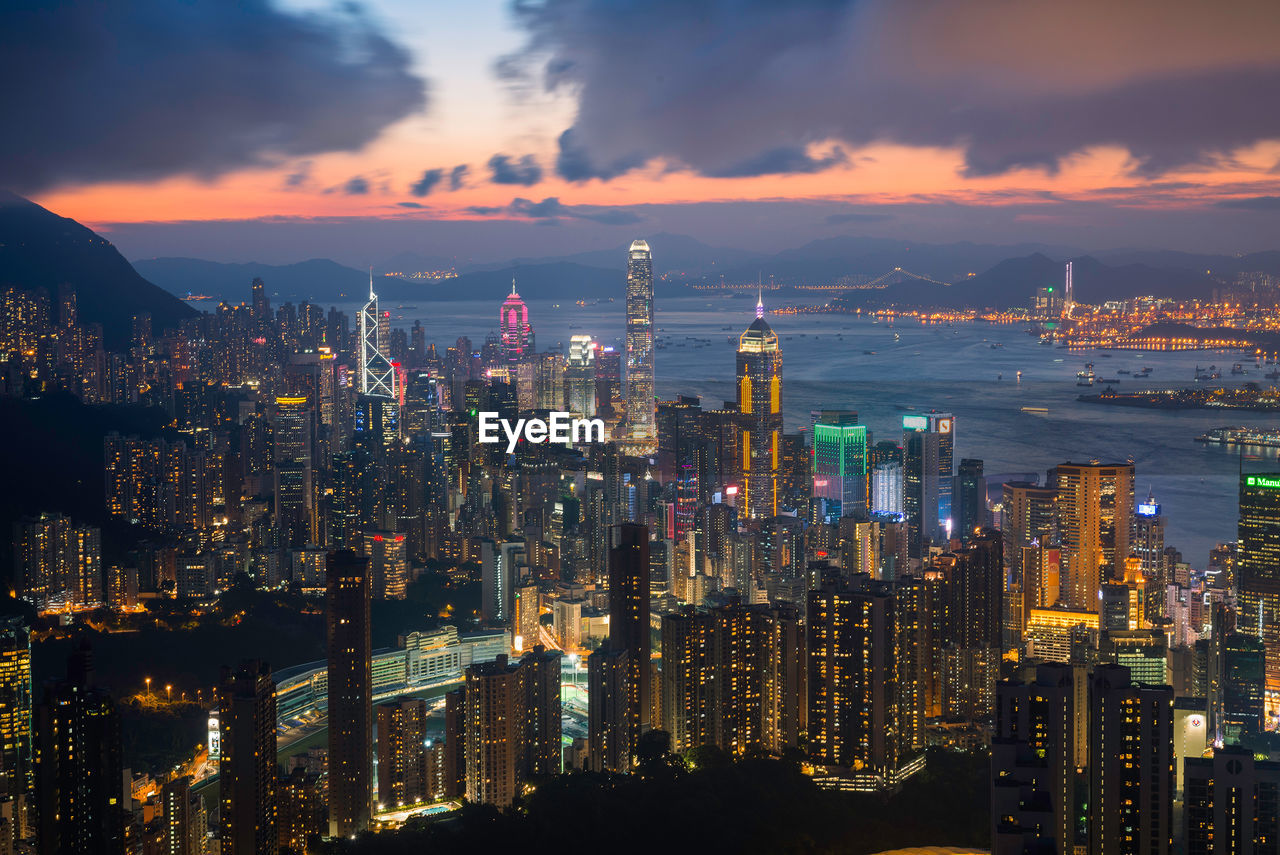 Illuminated cityscape against sky during sunset