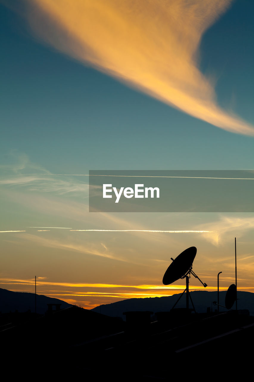 Silhouette of satellite dishes against sky during sunset