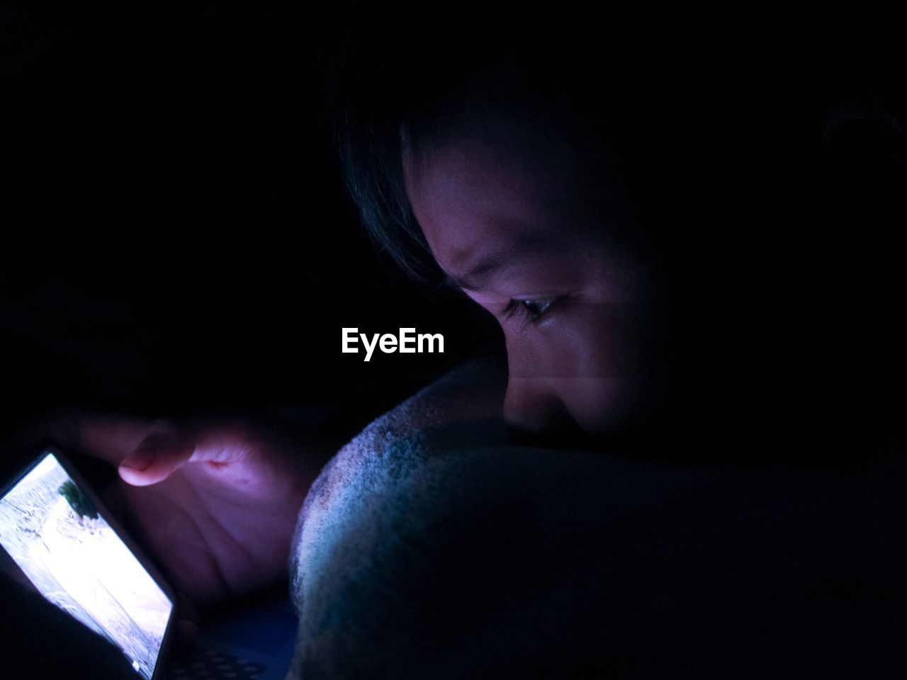 Close-up of boy using mobile phone against black background