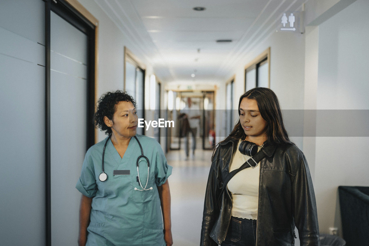 Female doctor discussing with patient while walking in corridor of hospital