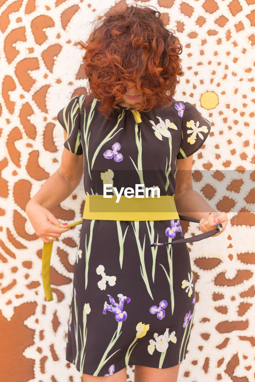 HIGH ANGLE VIEW OF WOMAN STANDING ON PATTERNED WALL