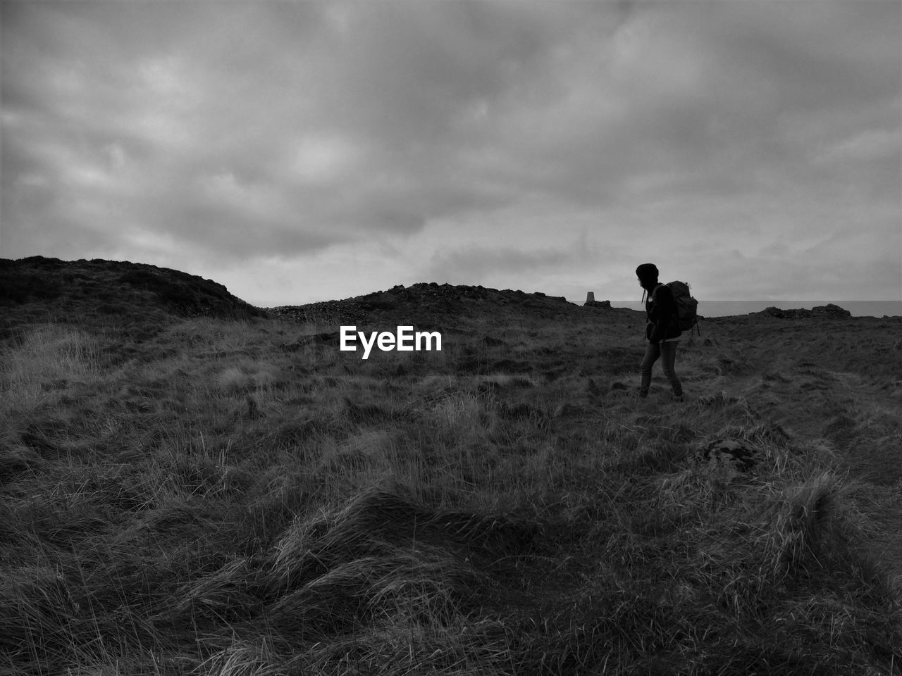 MAN WALKING ON FIELD AGAINST MOUNTAIN