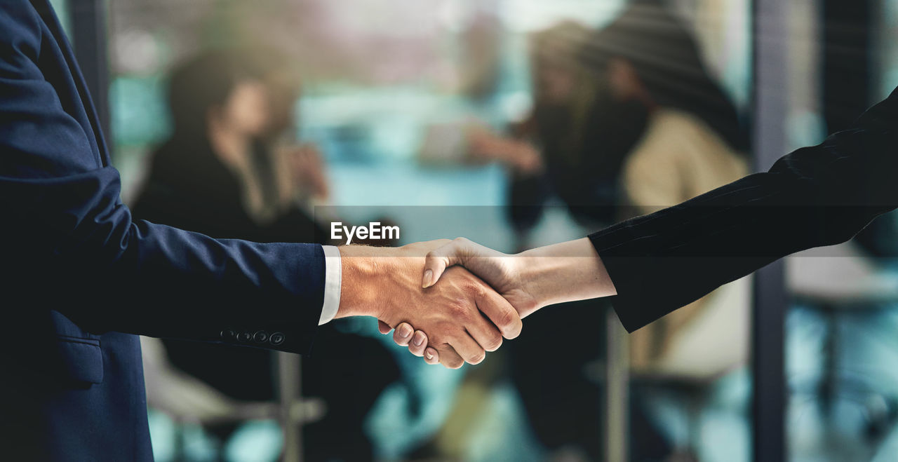 Midsection of business colleagues shaking hands