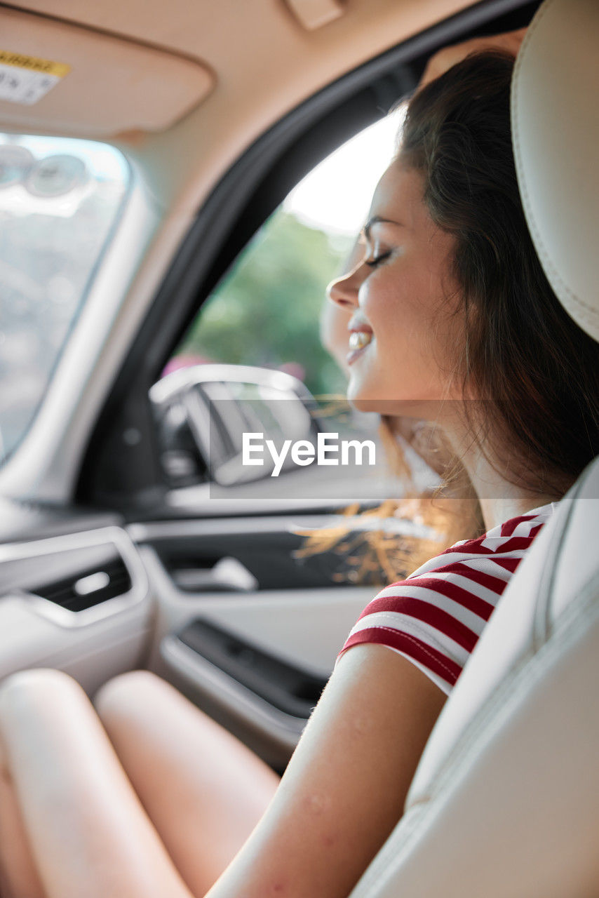 side view of young woman using mobile phone while sitting in car