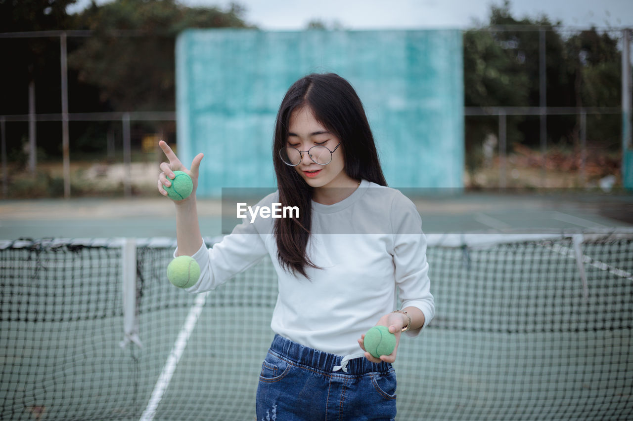 Young woman playing with balls at tennis court