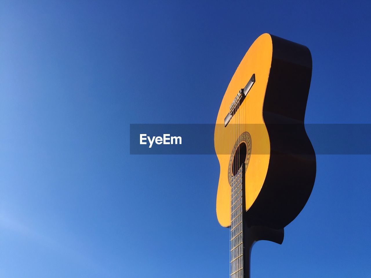 Low angle view of guitar against clear blue sky