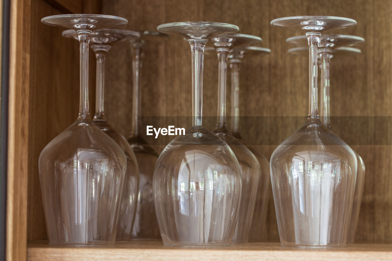 Close-up of wineglasses on wooden shelf