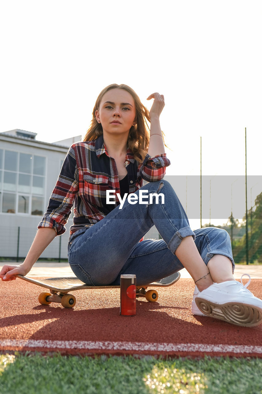Young millennial woman hippie sitting on skateboard. summer skate sessions. sport skateboarding. 