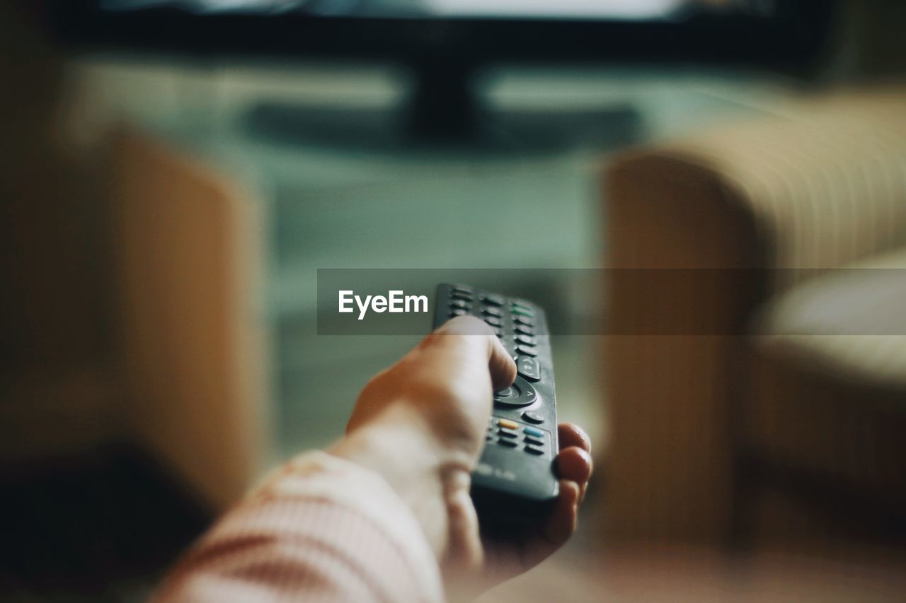 Cropped hand of woman holding remote control