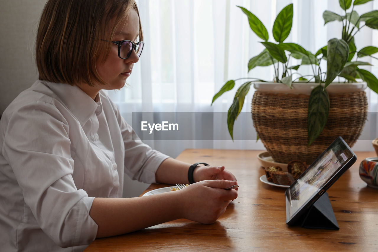 Girl eats lunch with tablet