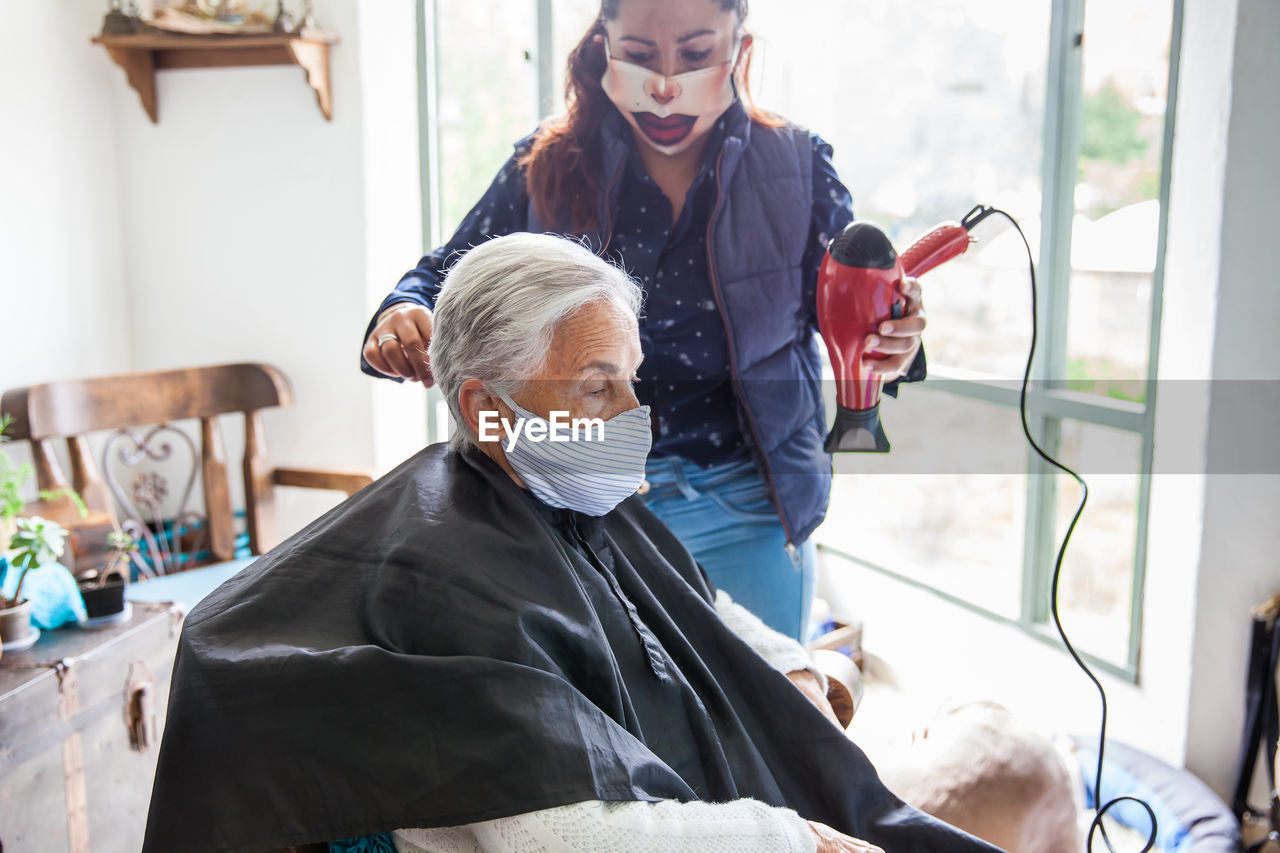 Beautician treating hair of customer at home