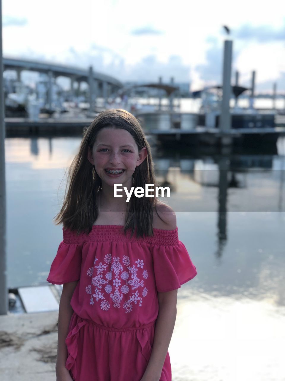 Portrait of smiling girl standing by sea against sky