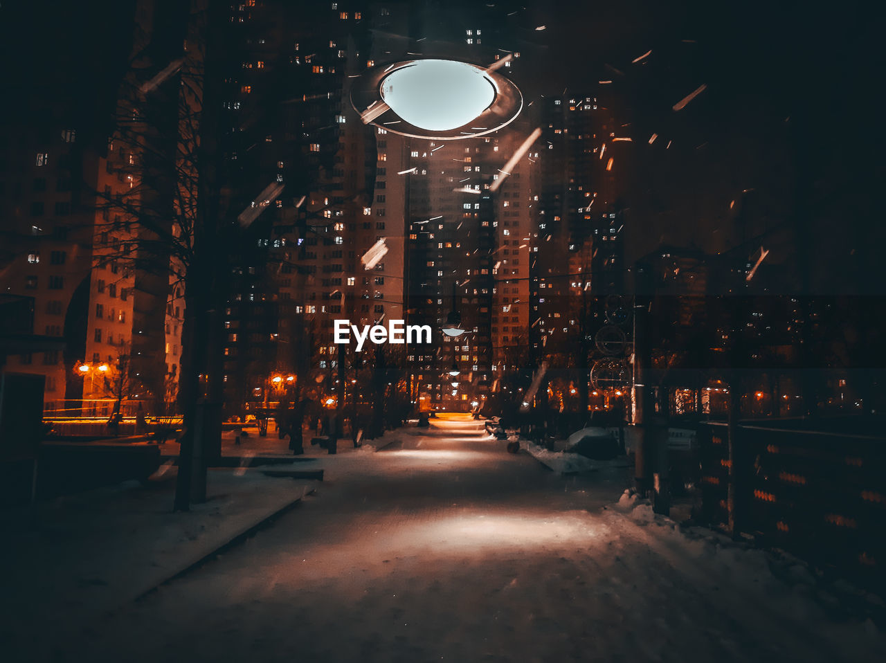 Illuminated street lights amidst buildings in city at night