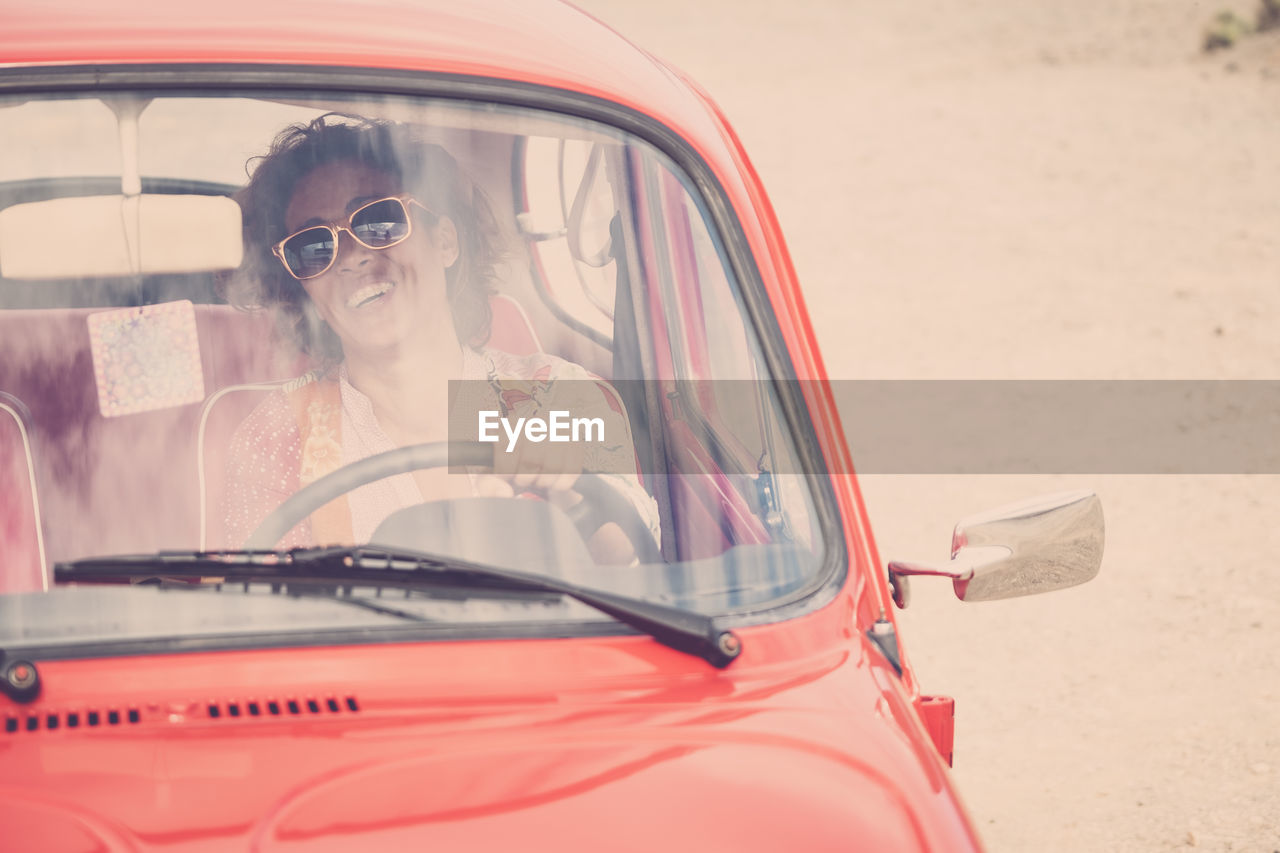 Smiling mature woman driving car seen through windshield