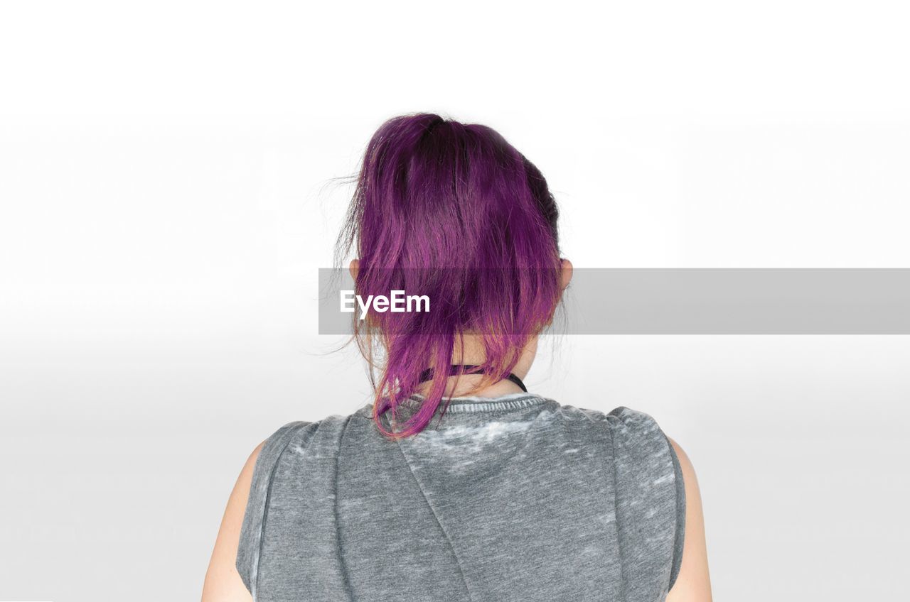Rear view of young woman with dyed hair against white background