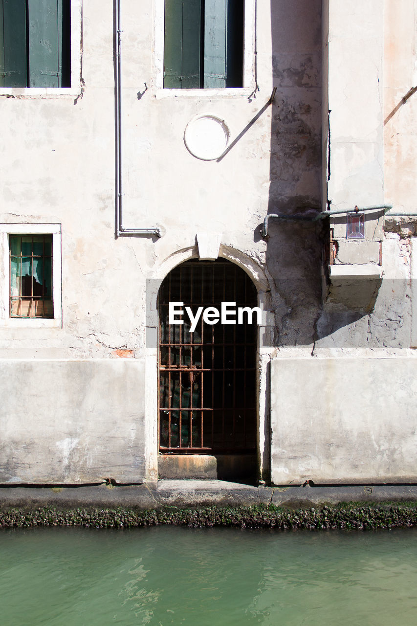 Frontal shot of the exterior of an old building  while the gate is close to the water