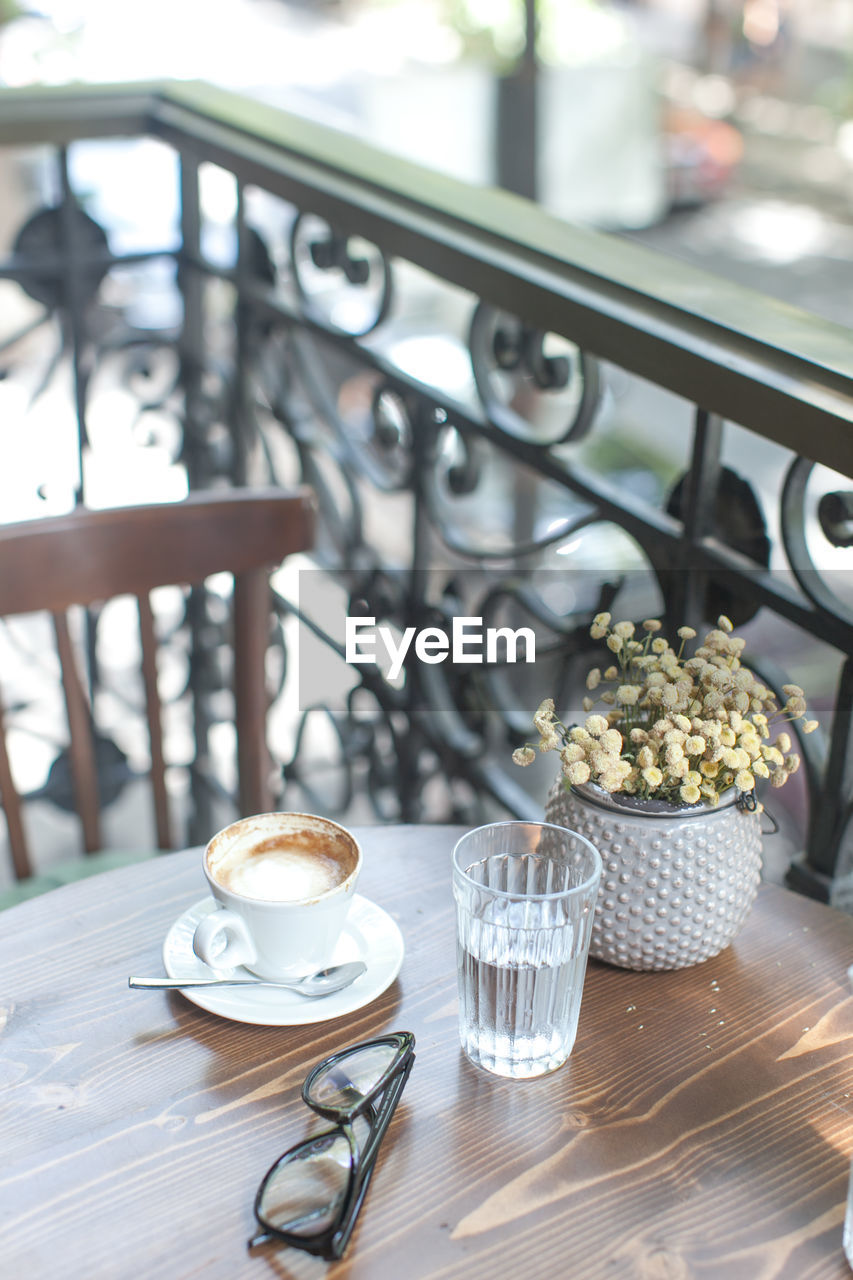 High angle view of coffee with eyeglasses on table at balcony