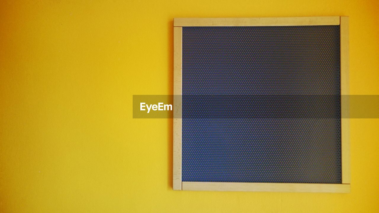 Close-up of black board on yellow wall