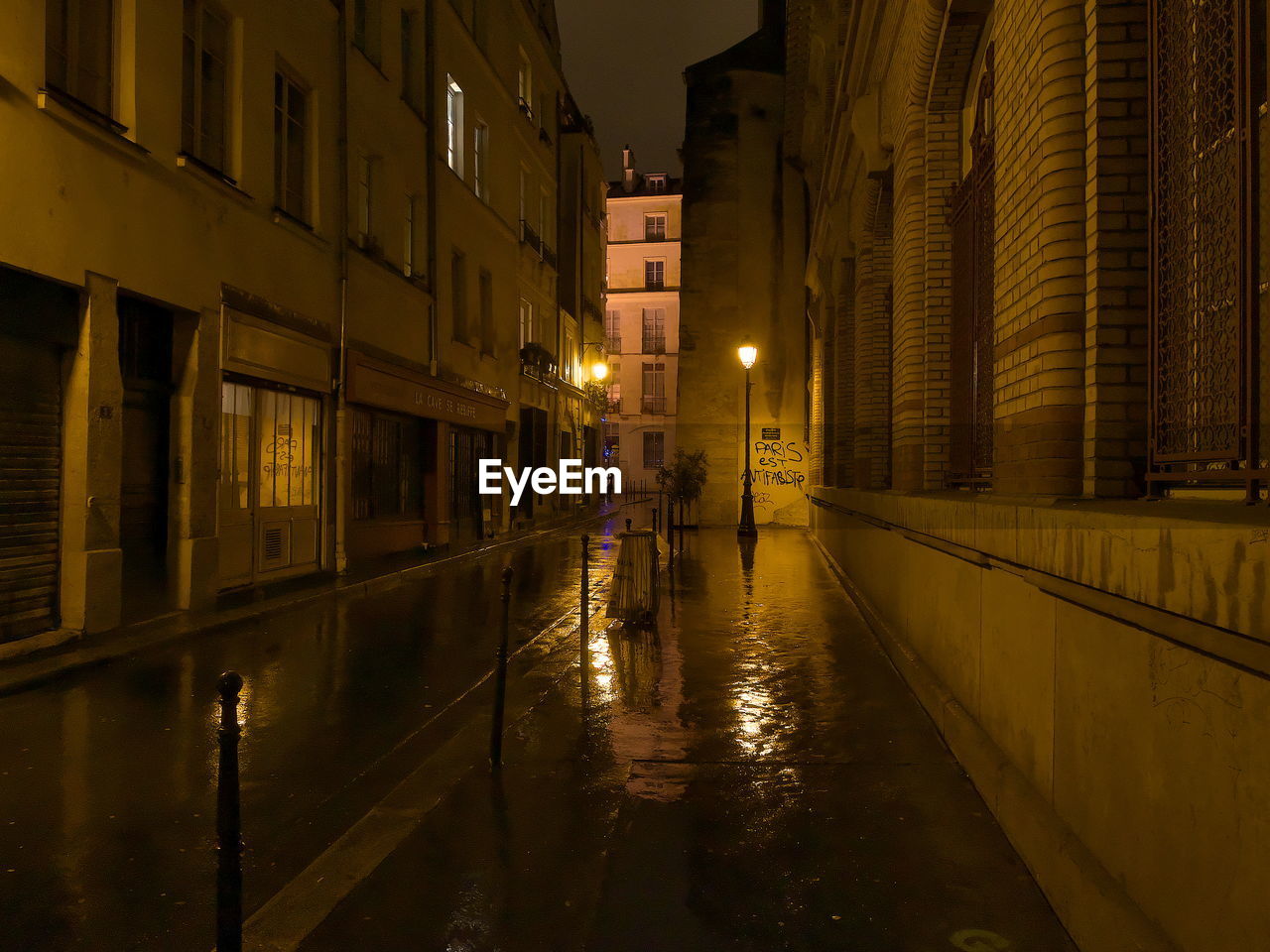 Illuminated street by city against sky at night