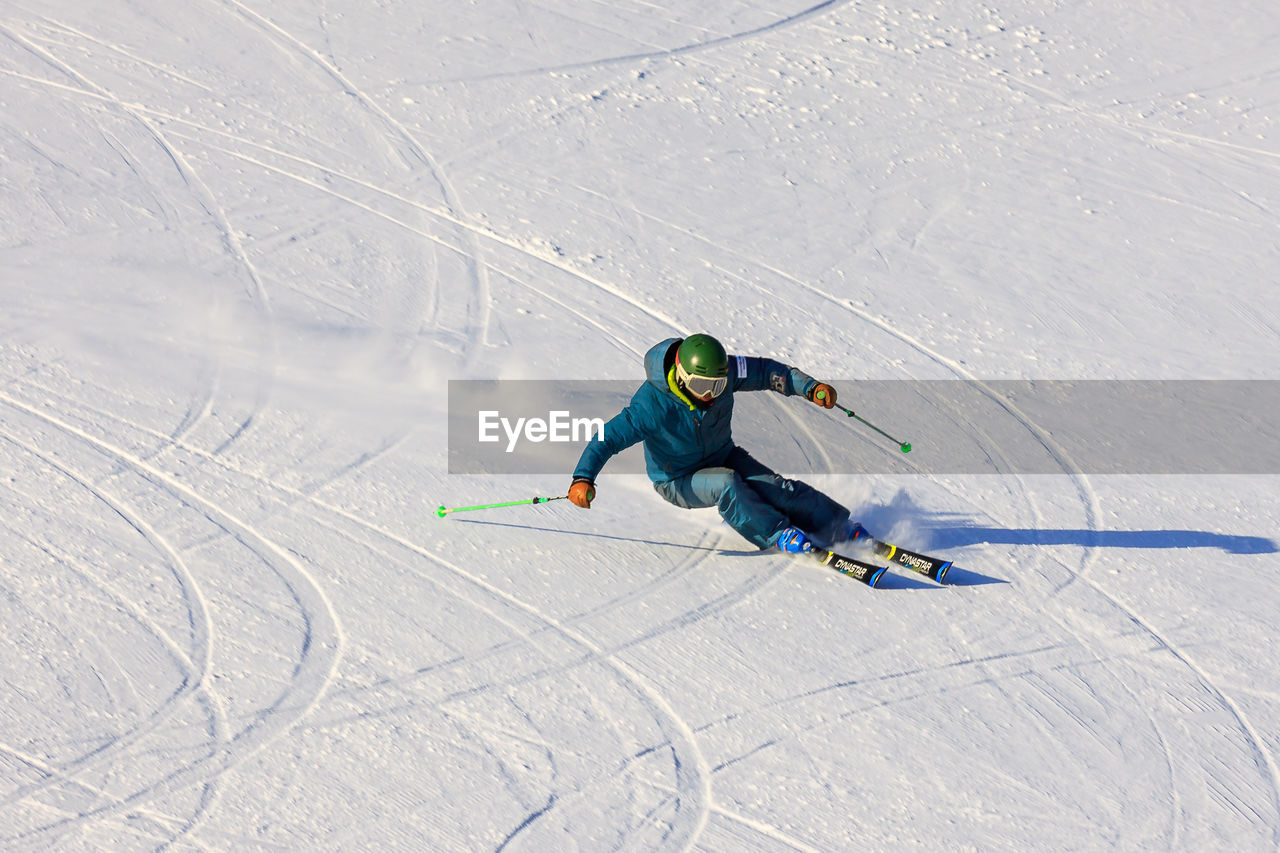 HIGH ANGLE VIEW OF PERSON SKIING ON SNOWY FIELD