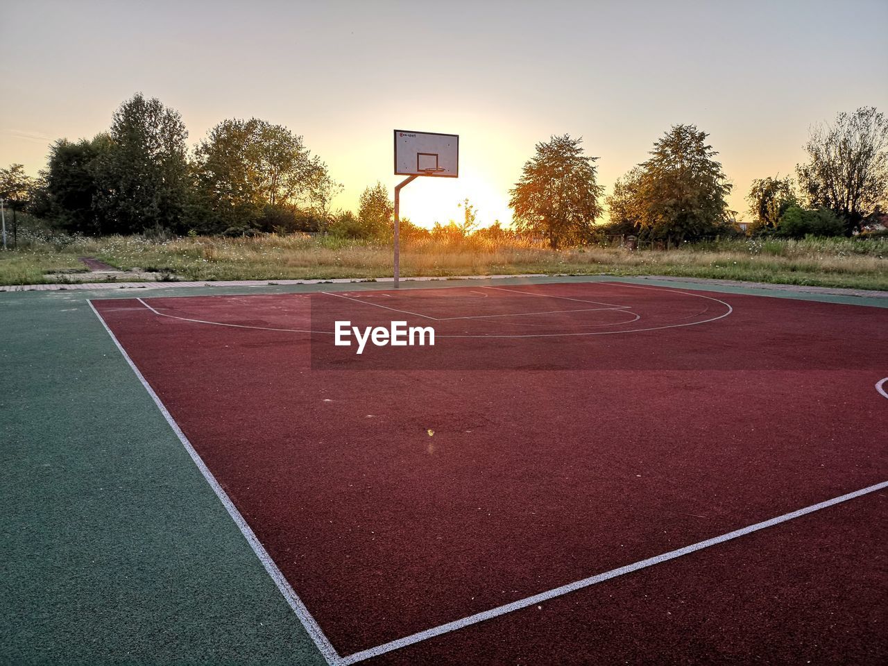 Basketball hoop in court against sky during sunset