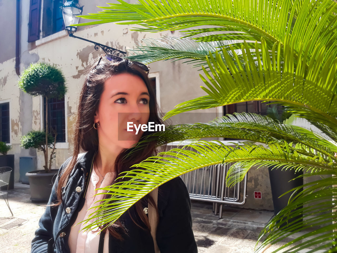 PORTRAIT OF BEAUTIFUL YOUNG WOMAN WITH PALM LEAVES