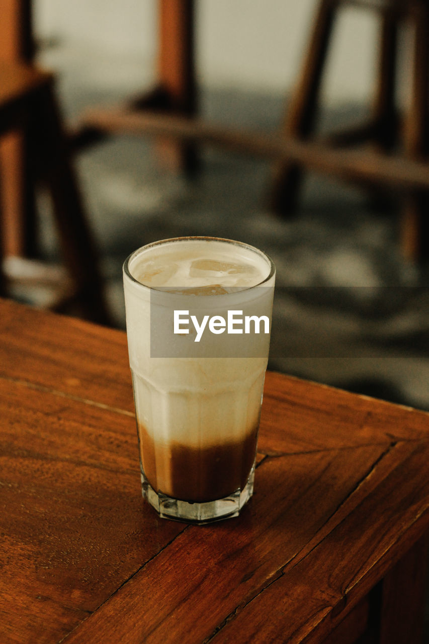 drink, refreshment, food and drink, drinking glass, glass, table, household equipment, alcoholic beverage, indoors, coffee, wood, focus on foreground, still life, frothy drink, no people, freshness, latte, cafe, close-up, alcohol, beer glass, hot drink, lighting, bar, food, beer