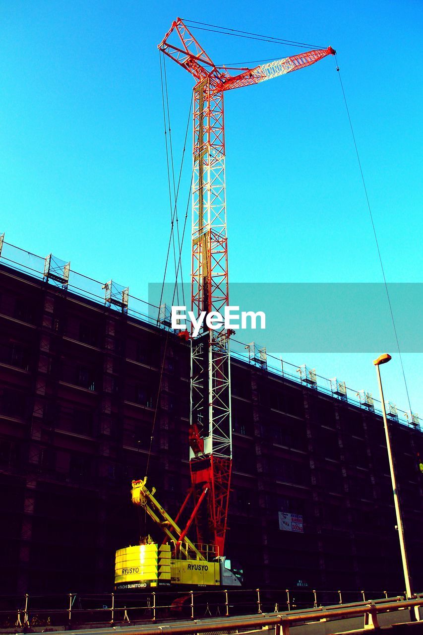 LOW ANGLE VIEW OF CRANES AGAINST CLEAR SKY