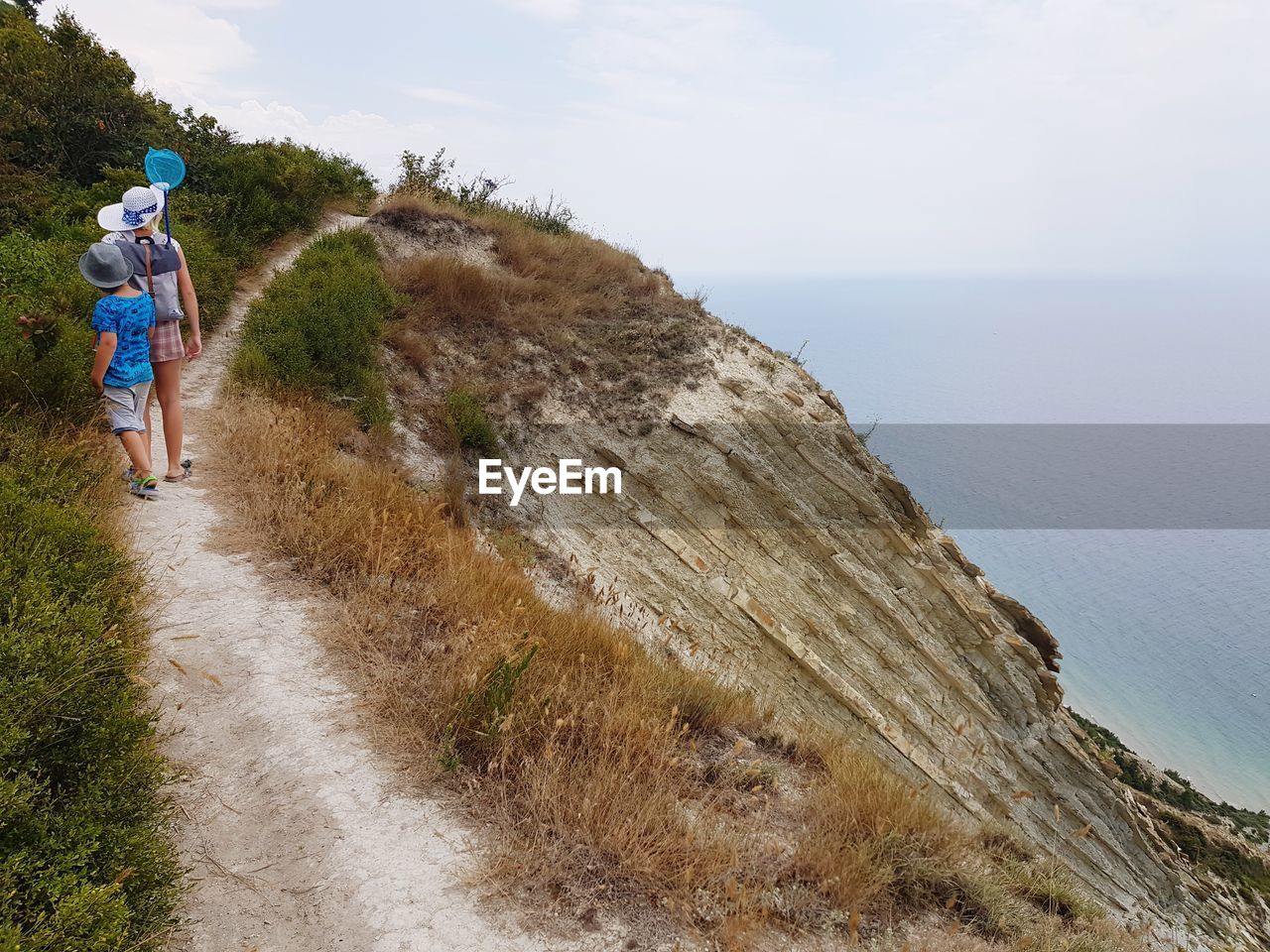 Rear view of mother with son walking on cliff