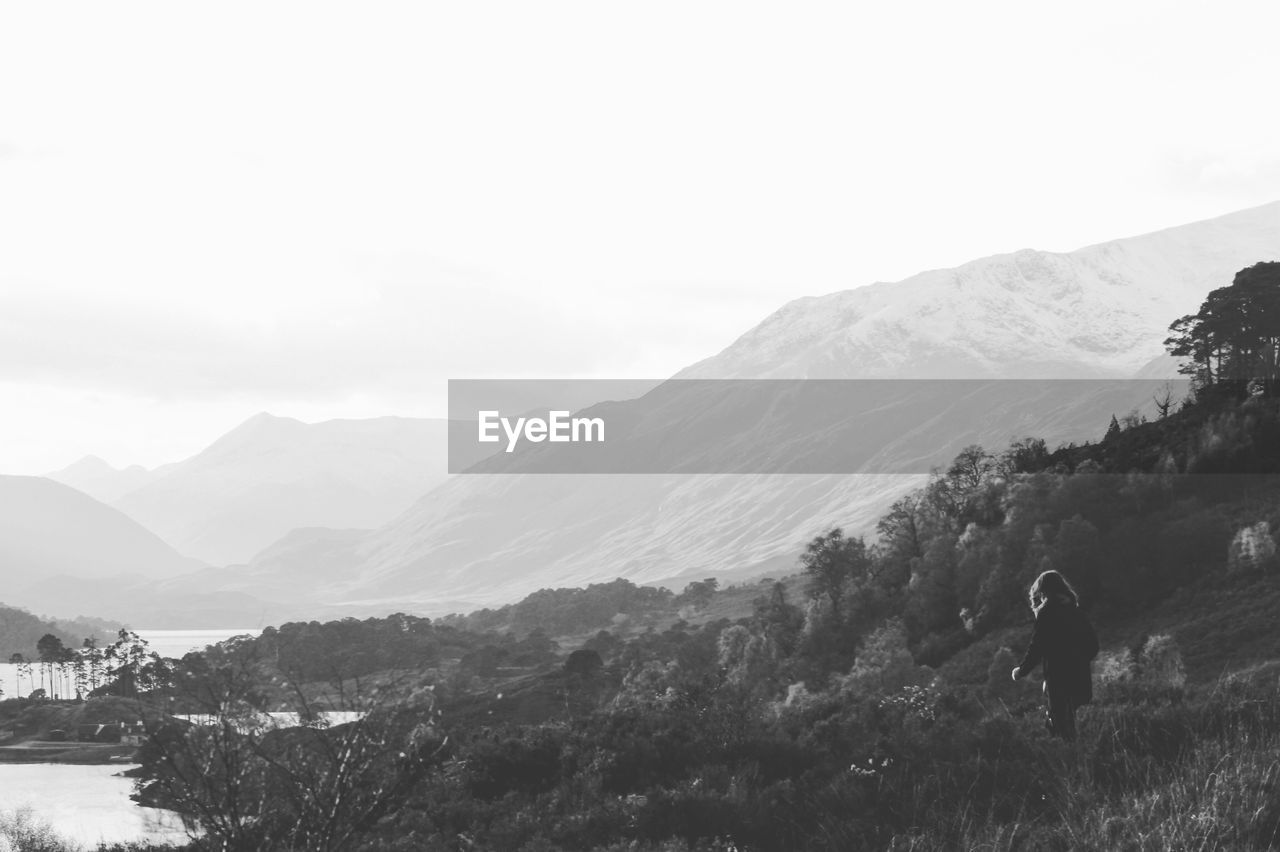 REAR VIEW OF MAN WALKING ON SNOWCAPPED MOUNTAIN