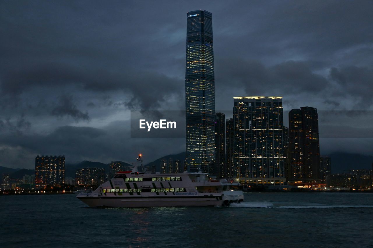 Ferry boat in victoria harbour against illuminated skyscrapers at dusk