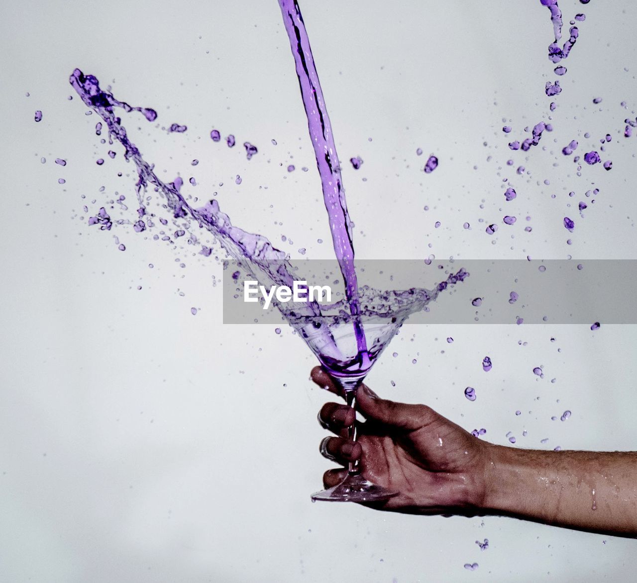 Cropped hand holding drink glass against white background