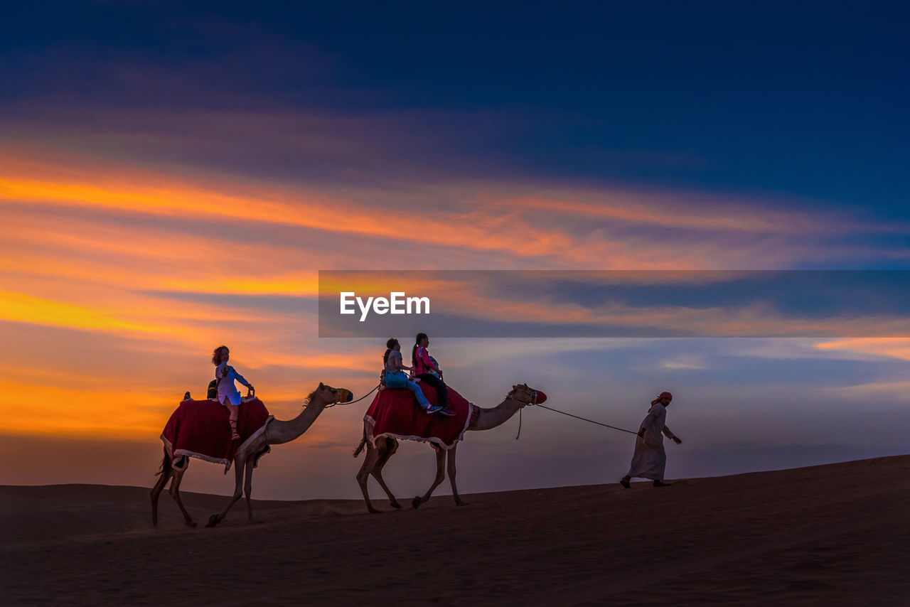 PEOPLE RIDING HORSE IN DESERT